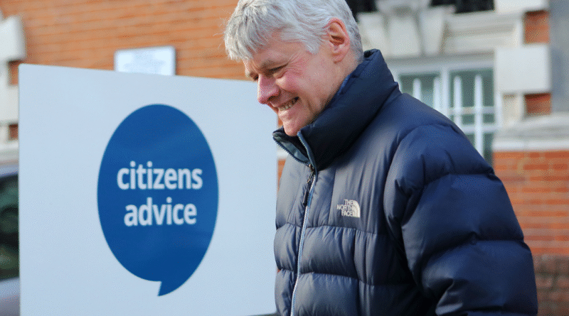 Photograph shows a man standing in front of a building with a Citizens Advice sign with text overlaid: #WeAreCitizensAdvice We are the people's champion